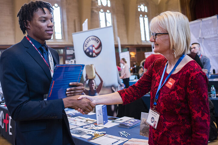A student meets with a Peace Corps representative at a job fair